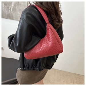Detail of red crescent shoulder bag featuring textured crocodile pattern leather and strap