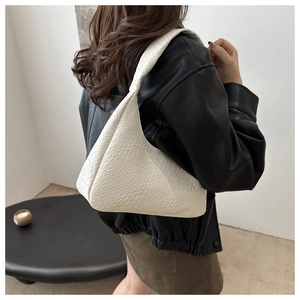 Détail de la texture tissée crème et de la silhouette triangulaire du sac porté épaule