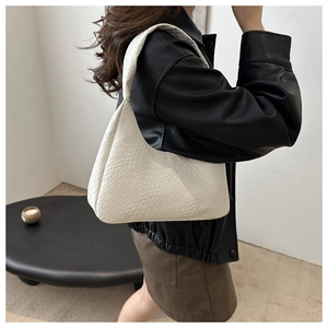 Fashionable beige woven crescent shoulder bag shown styled on a shoulder with daily outfit