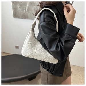 Close-up of white woven crescent bag featuring intricate checkerboard texture and half-moon shape