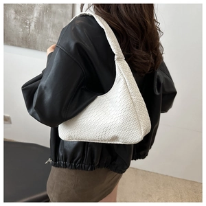 Close-up of white woven leather texture on a minimalist crescent hobo shoulder bag