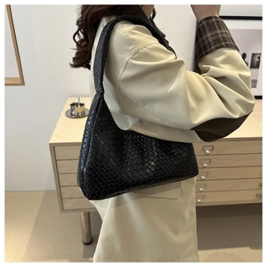 Detailed view of the black woven leather texture and integrated strap on a hobo bag