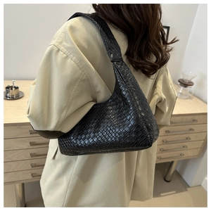 Detail of black woven leather crescent bag showing intricate texture on a female model