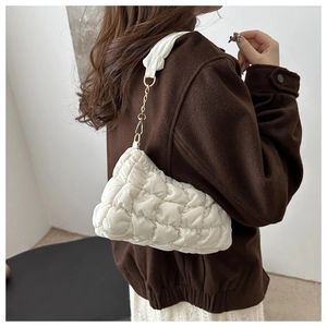 Detailed shot of white quilted puffy bag featuring a gold chain and ruched strap