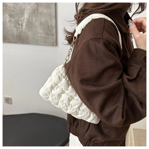 Detail view of white quilted cloud bag featuring soft pleated texture and gold chain strap