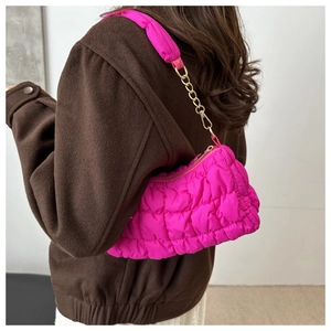 Detail of fuchsia quilted cloud bag with gold chain strap on a wool coat