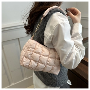 Close-up of a light pink quilted bubble fabric shoulder bag with golden chain and strap