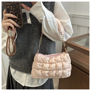 Detail of light pink quilted cloud bag featuring bubble texture and gold chain strap