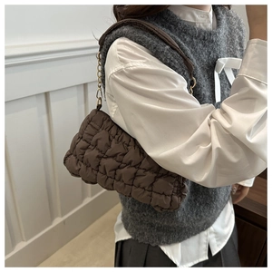 Detail of coffee brown quilted cloud bag with gold chain strap and soft bubble texture