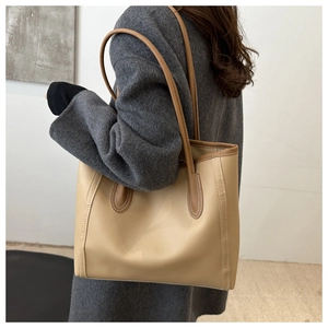 Detail of contrast stitching and brown handle attachment on cream PU leather tote bag