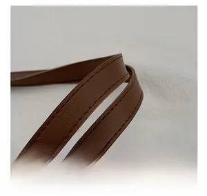 Detailed view of the dark brown leather strap with reinforced stitching on a tote bag