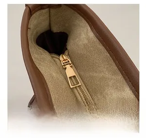 Detail of smooth gold zipper and pebble leather texture on a brown tote bag