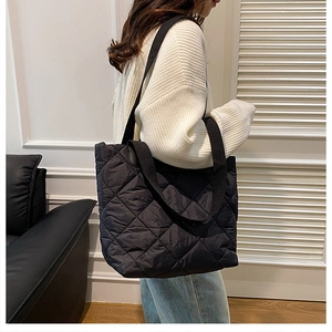 Détail macro du motif matelassé en losange sur un grand sac cabas noir en nylon