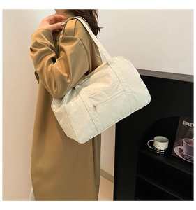 Detail of a beige nylon tote bag featuring a front zipper pocket for city commuting
