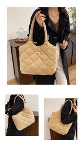 Detail of beige quilted tote bag featuring diamond stitching and gold deer pendant
