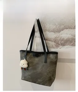 Detail of a large grey marbled tote bag with a white plush cloud charm and slim straps