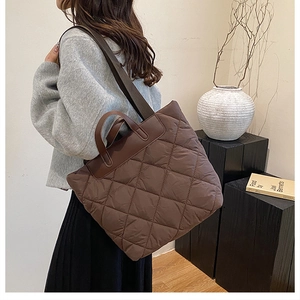 Sac fourre-tout matelassé en nylon marron foncé avec poignées en cuir sur modèle