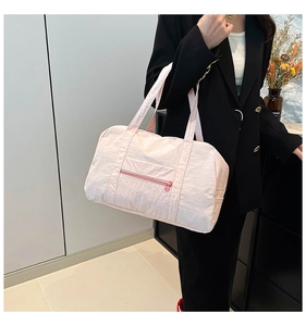 Light pink nylon travel bag worn by a model in a black blazer showing its large capacity