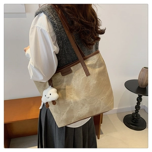 Détail d'un grand sac cabas en toile avec anses en cuir et charm nuage pelucheux