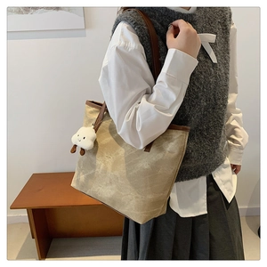 Detail of canvas tote bag with brown leather trim and cute cloud plush charm