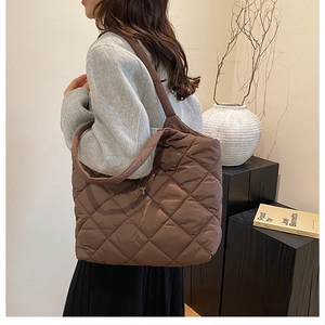 Quilted down-filled tote bag in dark brown with elegant stitching and metallic charm detail