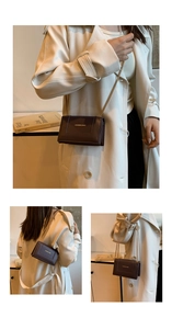 Detail of dark coffee leather crossbody bag featuring gold lettering and metal chain strap