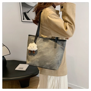Close-up of gray tote bag texture with fashion label and white cloud plush charm
