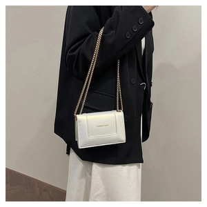 Chic white pearlescent square bag with gold chain strap shown on a dark blazer