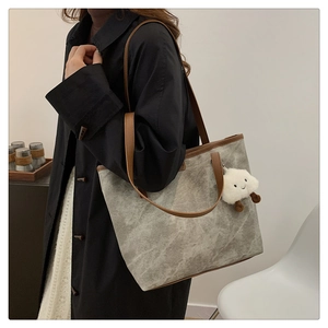 Close-up of marble pattern tote bag with plush cloud charm on a model in black coat