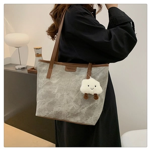 Détail du sac fourre-tout gris marbré avec anses marron foncé et breloque en peluche douce
