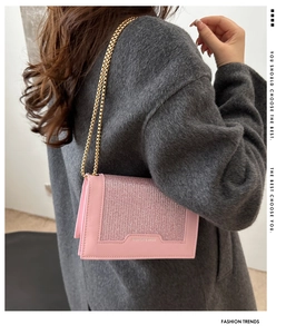 Détail latéral du sac à bandoulière rose pailleté avec chaîne dorée porté par un mannequin