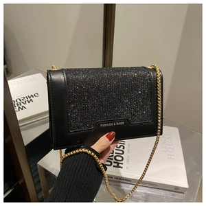 Détail d'un sac bandoulière noir avec rabat pailleté coloré et bandoulière chaîne dorée