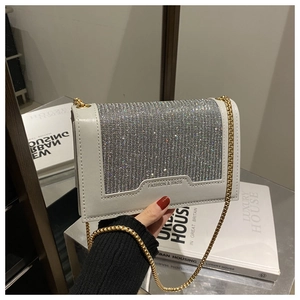 Gros plan d'un sac à bandoulière blanc orné de strass argentés et d'une chaîne dorée
