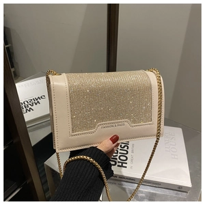 Détail d'un sac bandoulière beige orné de strass brillants et d'une bandoulière chaîne dorée
