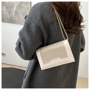 Détail du sac bandoulière beige à paillettes avec chaîne dorée et gravure de mode