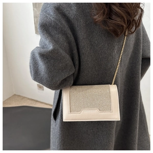 Détail du sac bandoulière blanc cassé avec rabat pailleté et chaîne dorée sur manteau