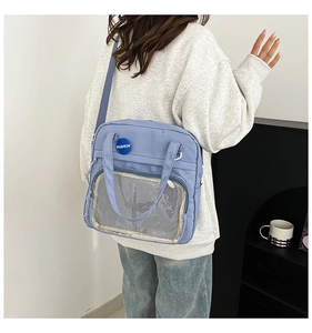 Detalle del bolso azul claro con bolsillo de malla transparente y escudo de moda