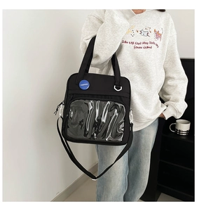 Detalle del bolso ita de lona negra con un gran bolsillo transparente y emblema de moda azul