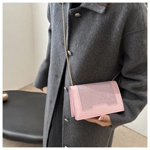 Sac à bandoulière rose scintillant avec chaîne dorée sur fond de manteau en laine gris