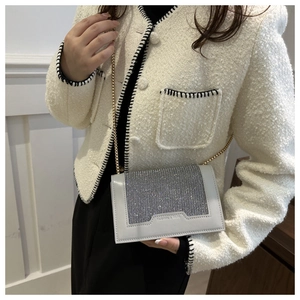 Détail de la surface en strass étincelants et chaîne dorée sur un sac bandoulière gris