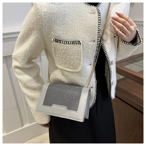 Détail d'un sac bandoulière gris avec rabat en strass et chaîne en métal élégante