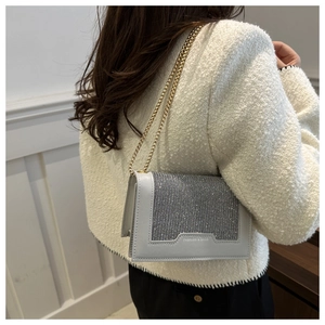 Détail d'un sac à chaîne en strass brillant porté avec une veste en tweed blanche chic