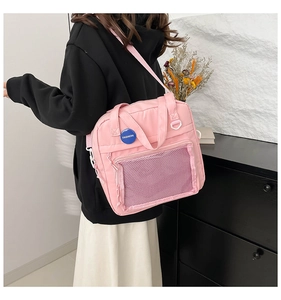 Detalle de bolso rosa de nailon con bolsillo de malla transparente y emblema azul de moda