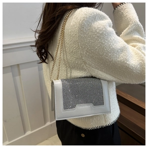 Détail de la chaîne dorée et du rabat incrusté de strass brillants sur le sac à bandoulière