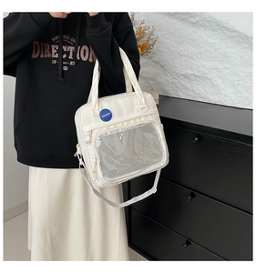 Detalle del bolso de nailon blanco roto con bolsillo de malla y placa redonda azul