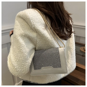 Vue détaillée du sac bandoulière argenté avec strass et chaîne dorée sur veste en tweed