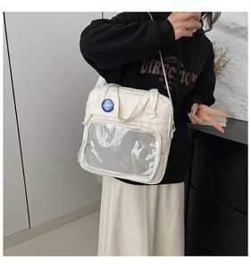 Detalle de bolso crema con bolsillo frontal de malla transparente y escudo azul de moda