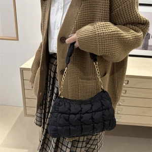 Quilted black cloud shoulder bag with gold chain strap worn with casual knitwear