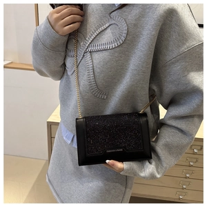 Gros plan du sac bandoulière à paillettes noires avec chaîne dorée et détail logo