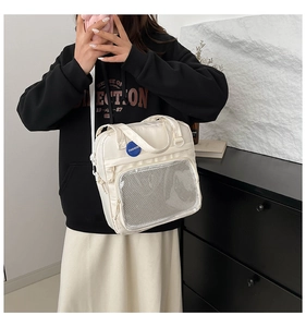 Detalle de bolso bandolera crema con bolsillo de malla frontal y logo azul de moda